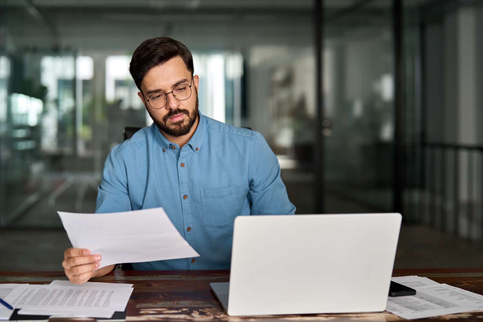 Busy business man checking documents working at laptop in office.